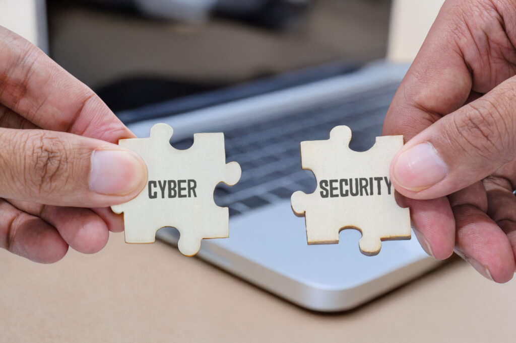 Hands holding two wooden jigsaw pieces, saying Cyber and Security to denote cyber security support